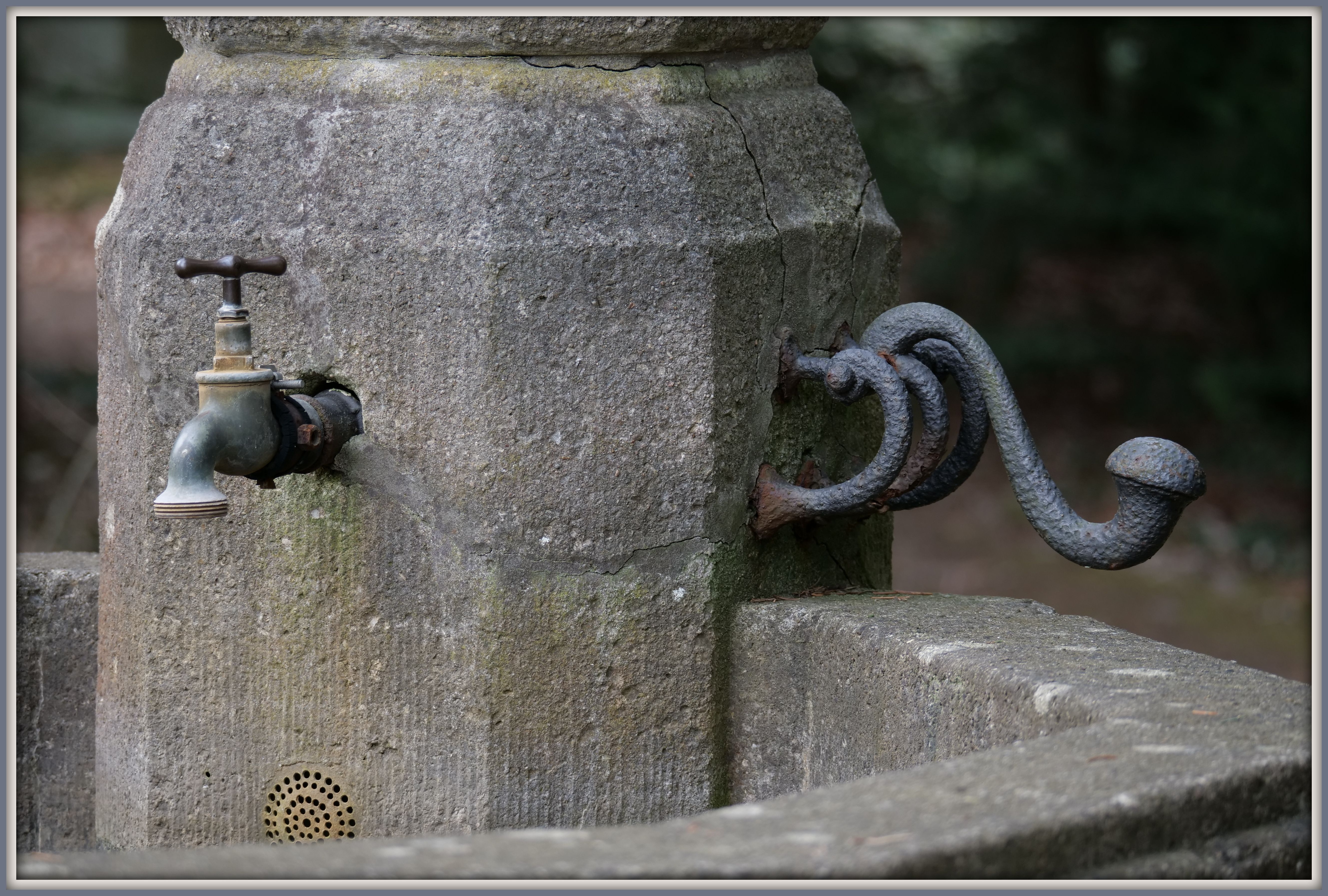 Historic stone fountain with tap and iron fitting at Parkfriedhof Lichterfelde
